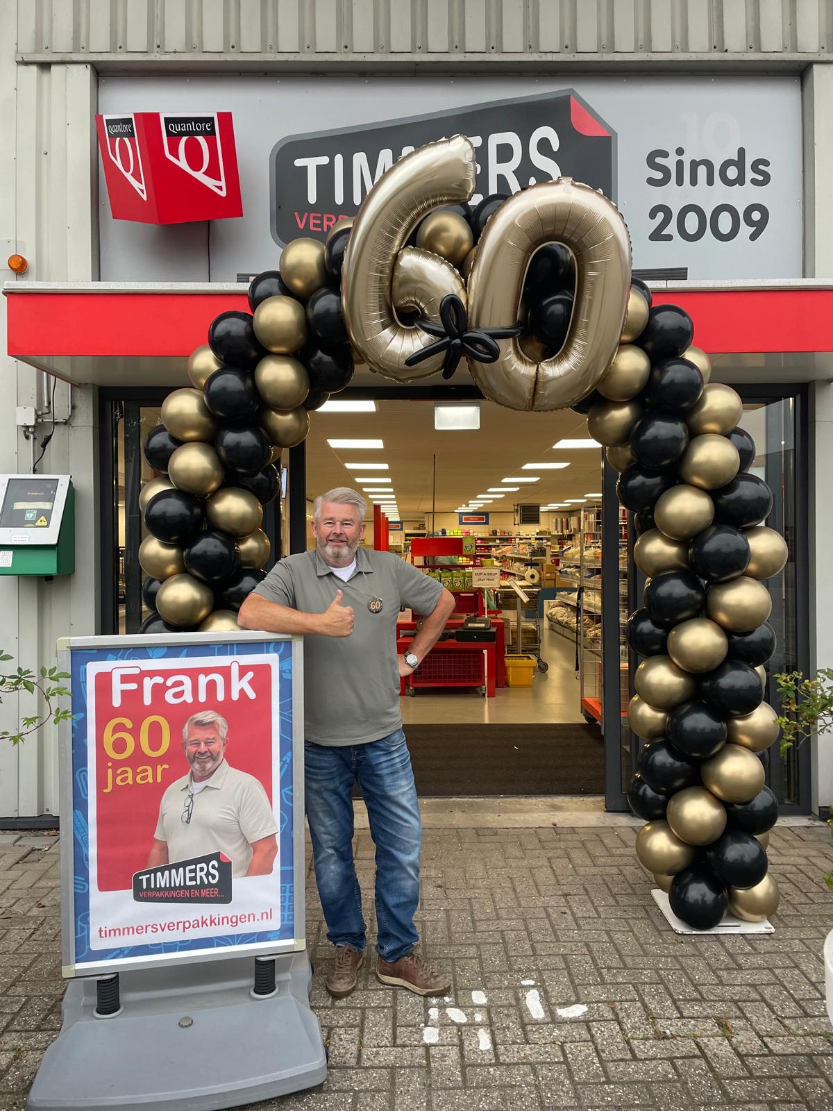Frank viert zijn 60e verjaardag bij de winkel met een ballonnenboog met gouden 60